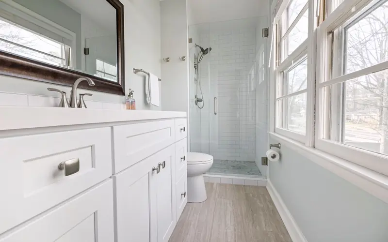 Bathroom with a white vanity, large mirror and glass shower door